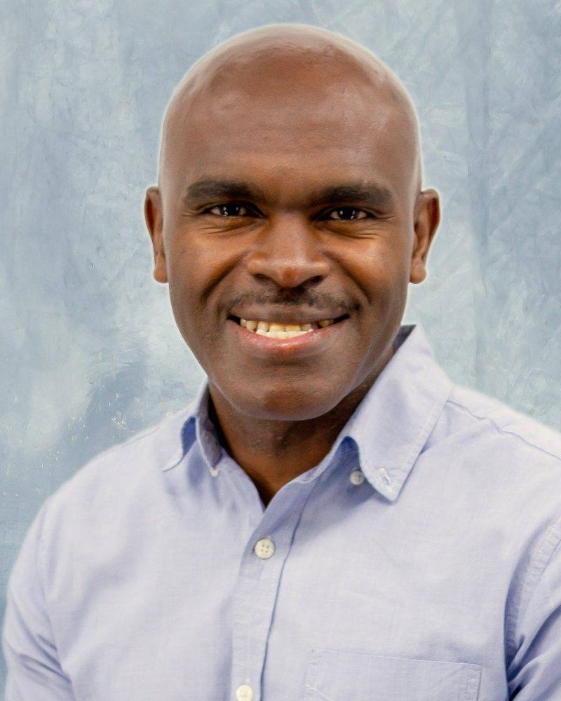 Alrick Watson, counsellor, smiling, in a light blue shirt against a pale studio backdrop