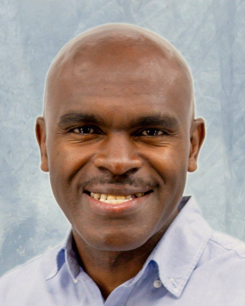Alrick Watson, counsellor, smiling, in a light blue shirt against a pale studio backdrop